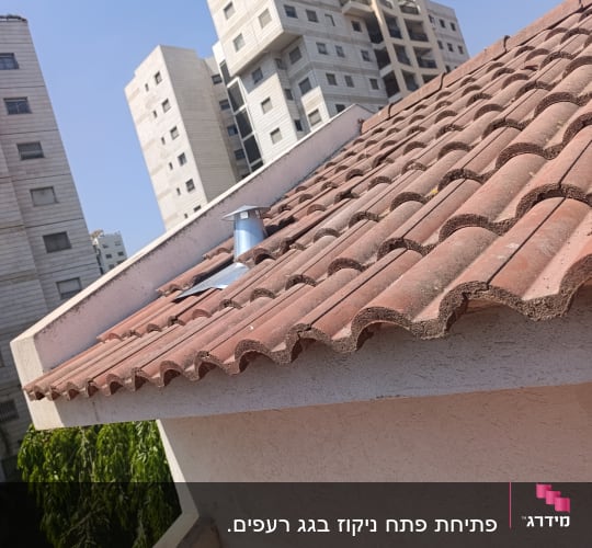 גג רעפים עם בניינים ברקע ביום שמשי